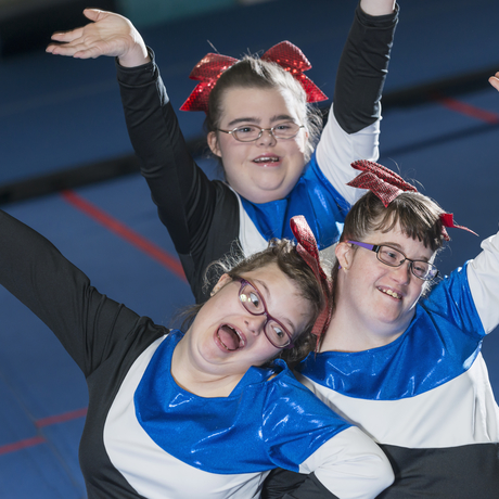 A group of three girls with Down syndrome on a cheerleading team.