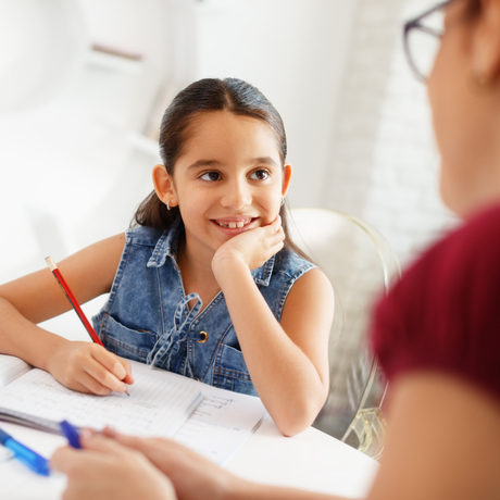 Child doing homework with adult watching.