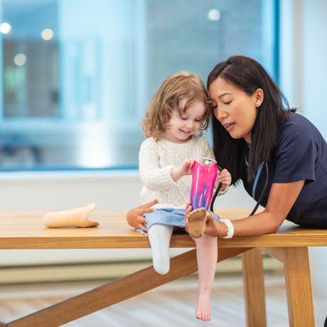Child with a prosthetic leg listening intently to her medical provider.