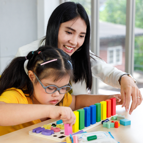 Girl with Down syndrome plays with her teacher.