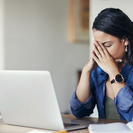 Shot of woman looking stressed while using a laptop.