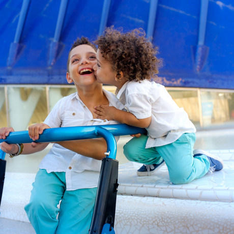 Two children, one with cerebral palsy hugging. 