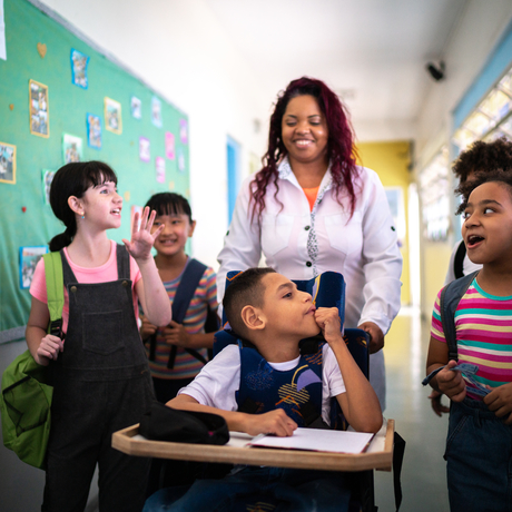 Teacher and students walking in the corridor at school—including a person with special needs.