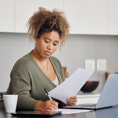 Woman filling out a form while sitting in front of a computer.